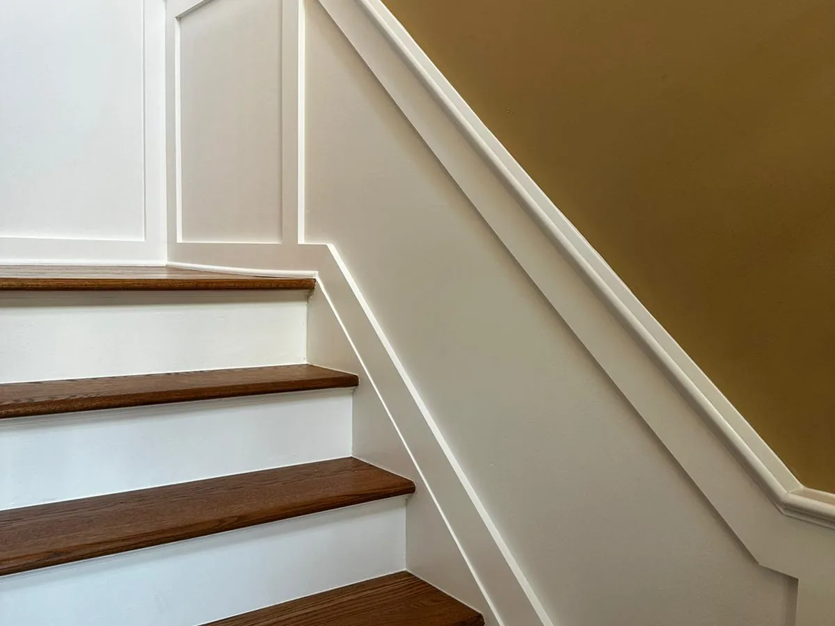 Refinished oak stair treads beside painted wainscot panelling