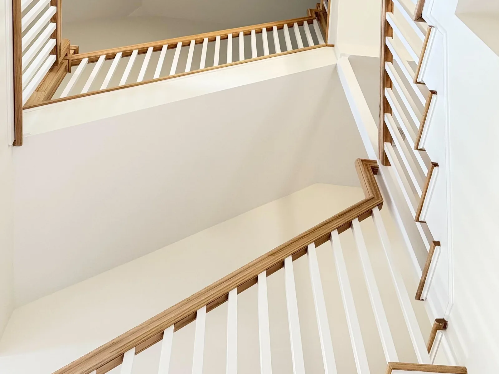 Oak handrail and white balusters wrapping an open landing in a New Jersey home